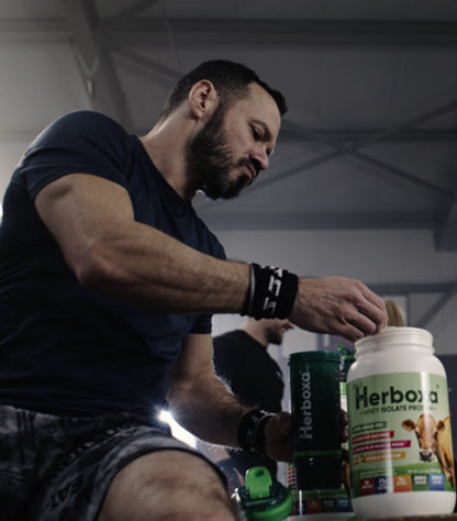 Man working out in the gym, preparing a Herboxa Whey Isolate Protein shake for muscle growth.